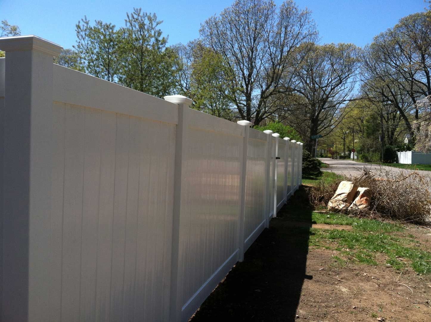 White vinyl fence in a residential setting on a sunny day.