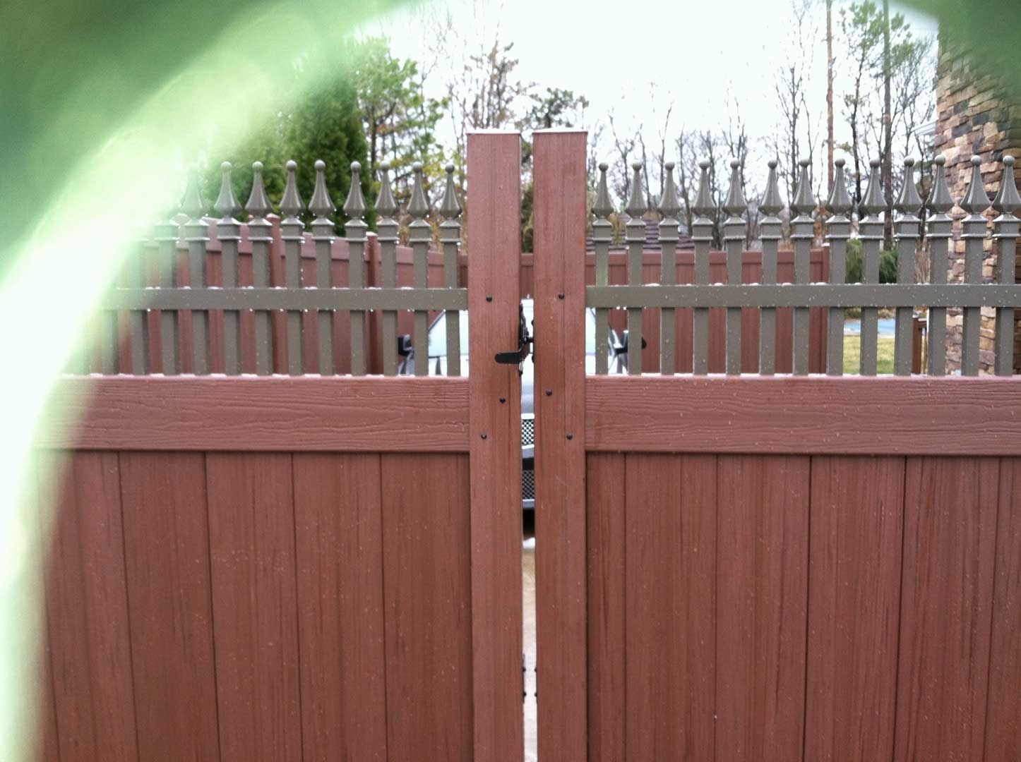 Brown wooden gate with a matching fence in the background, likely providing property access.