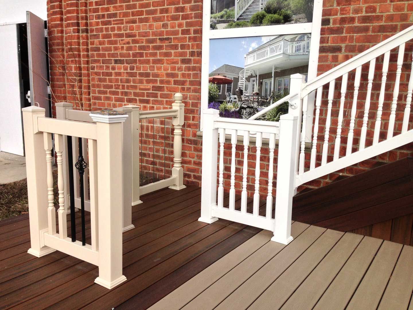 Outdoor deck with white railing and stairs against a brick wall.