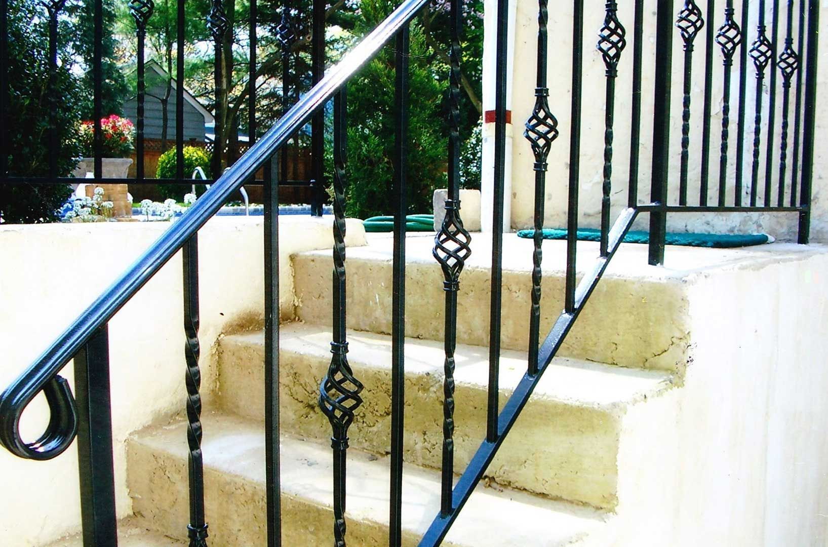 Black metal railing along outdoor concrete stairs.