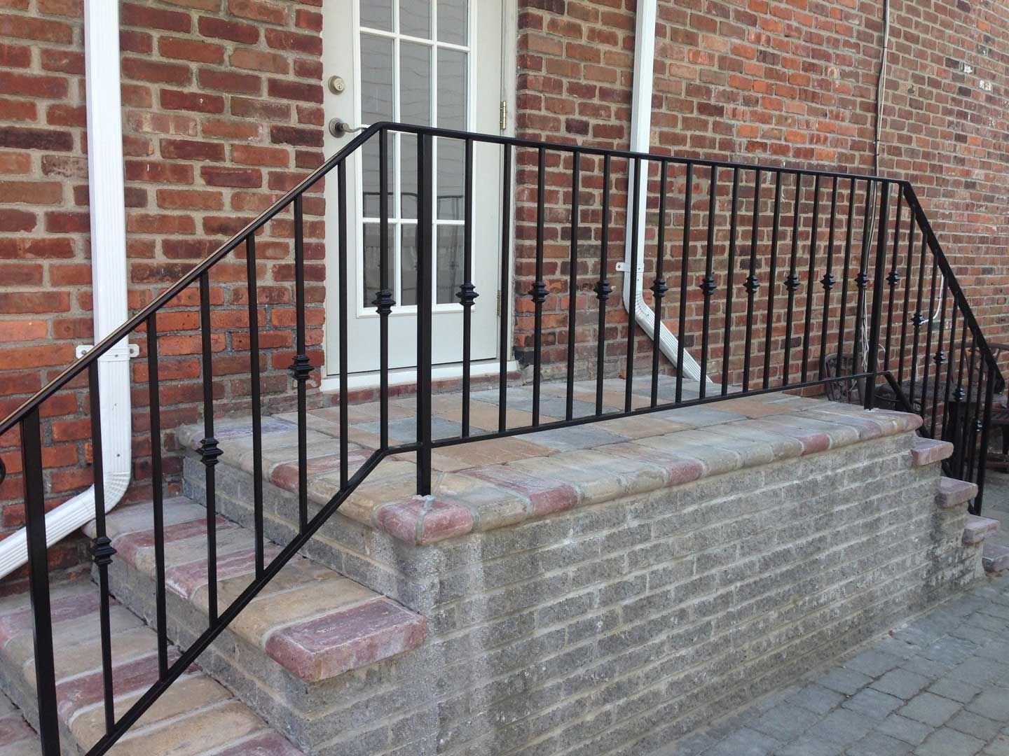 Brick steps with black wrought iron handrails leading to a white door.