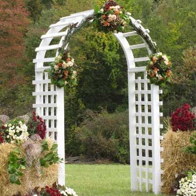 White trellis arch decorated with flowers in a garden setting.