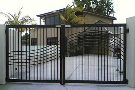 Black wrought iron driveway gates in front of a house.