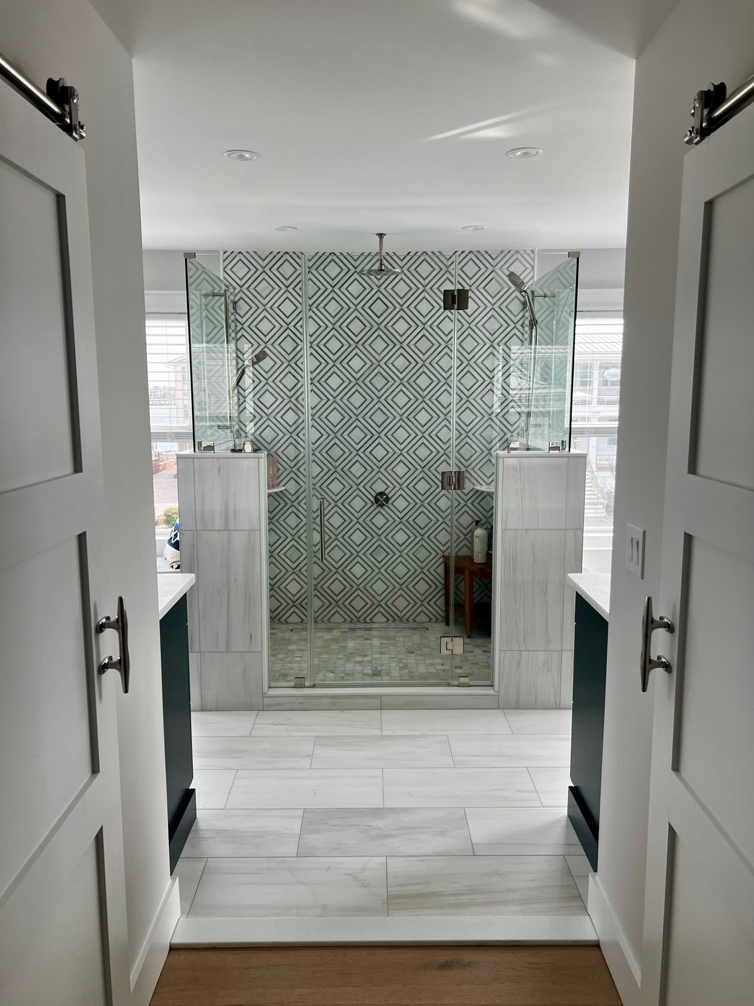 Bathroom with open shower, patterned tile accent wall, white and gray color scheme.