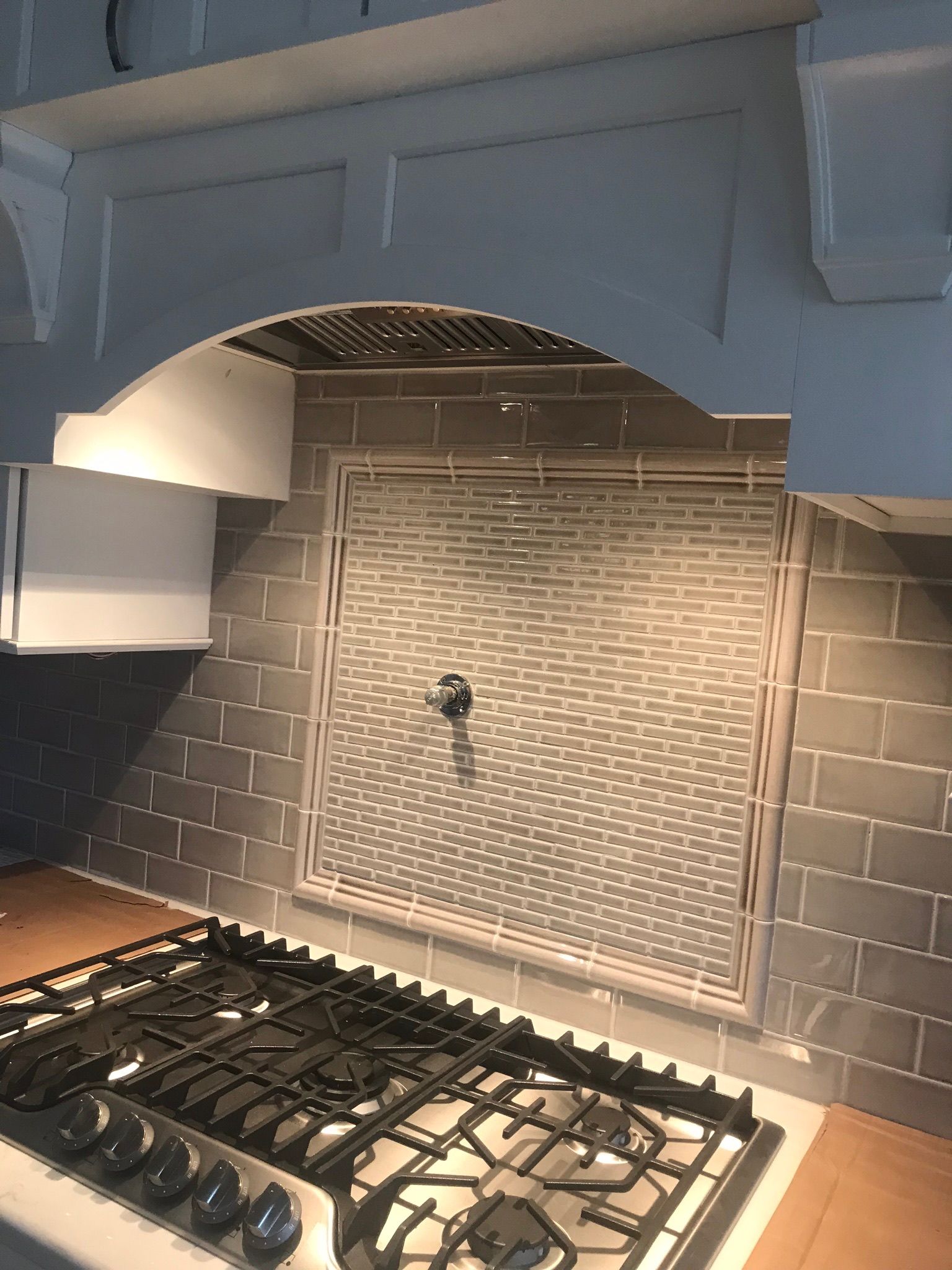 Kitchen with gas stove, tiled backsplash, and decorative range hood.