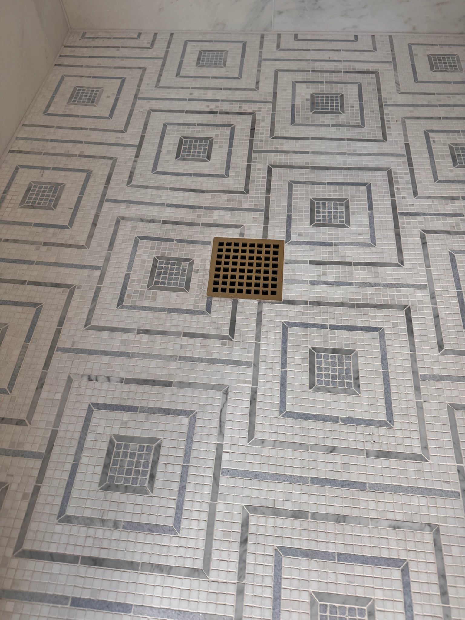 Shower floor with mosaic tile pattern and central drain.