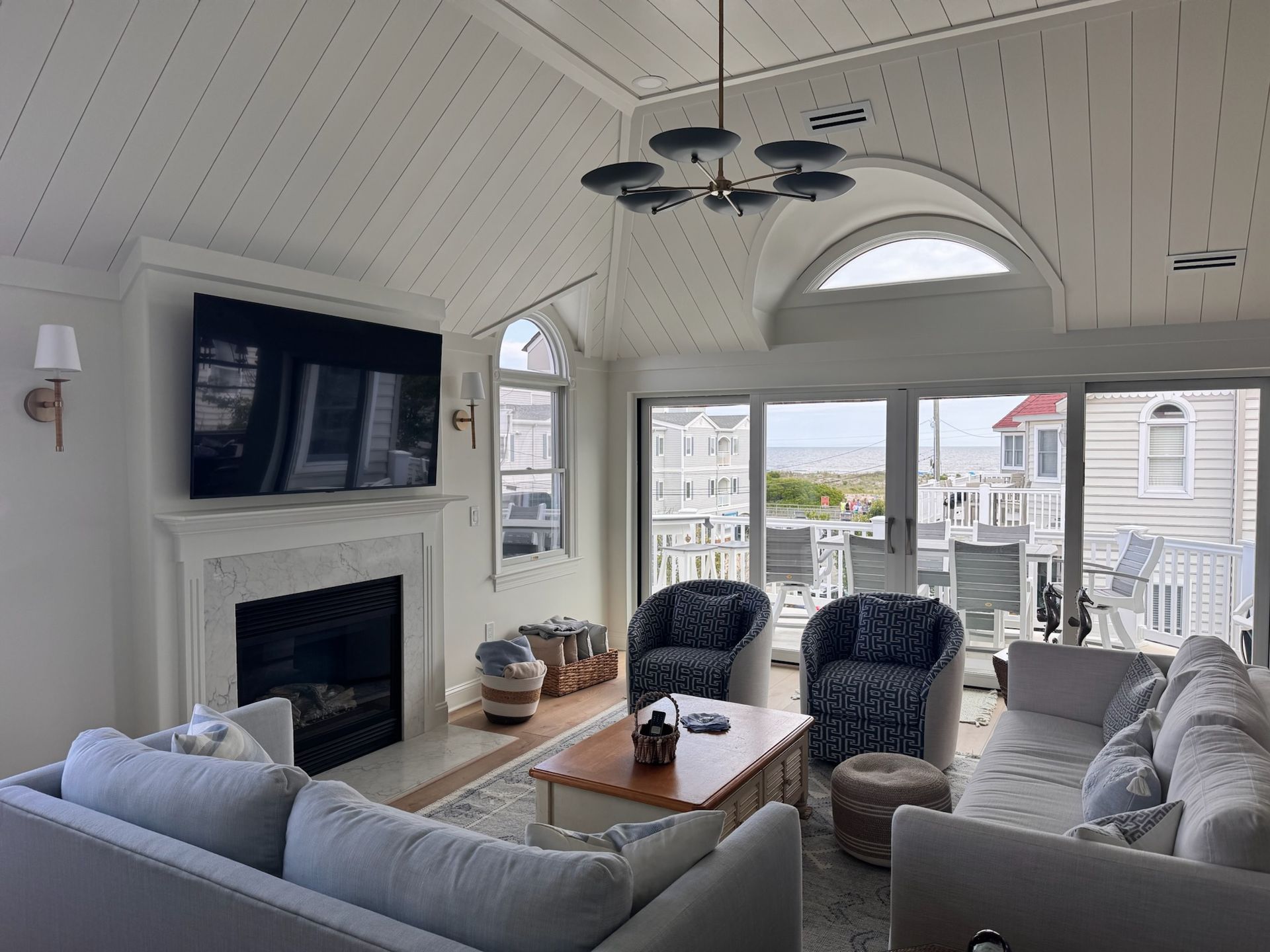 Living room with fireplace, sofas, and waterfront view. White walls, wood ceiling.