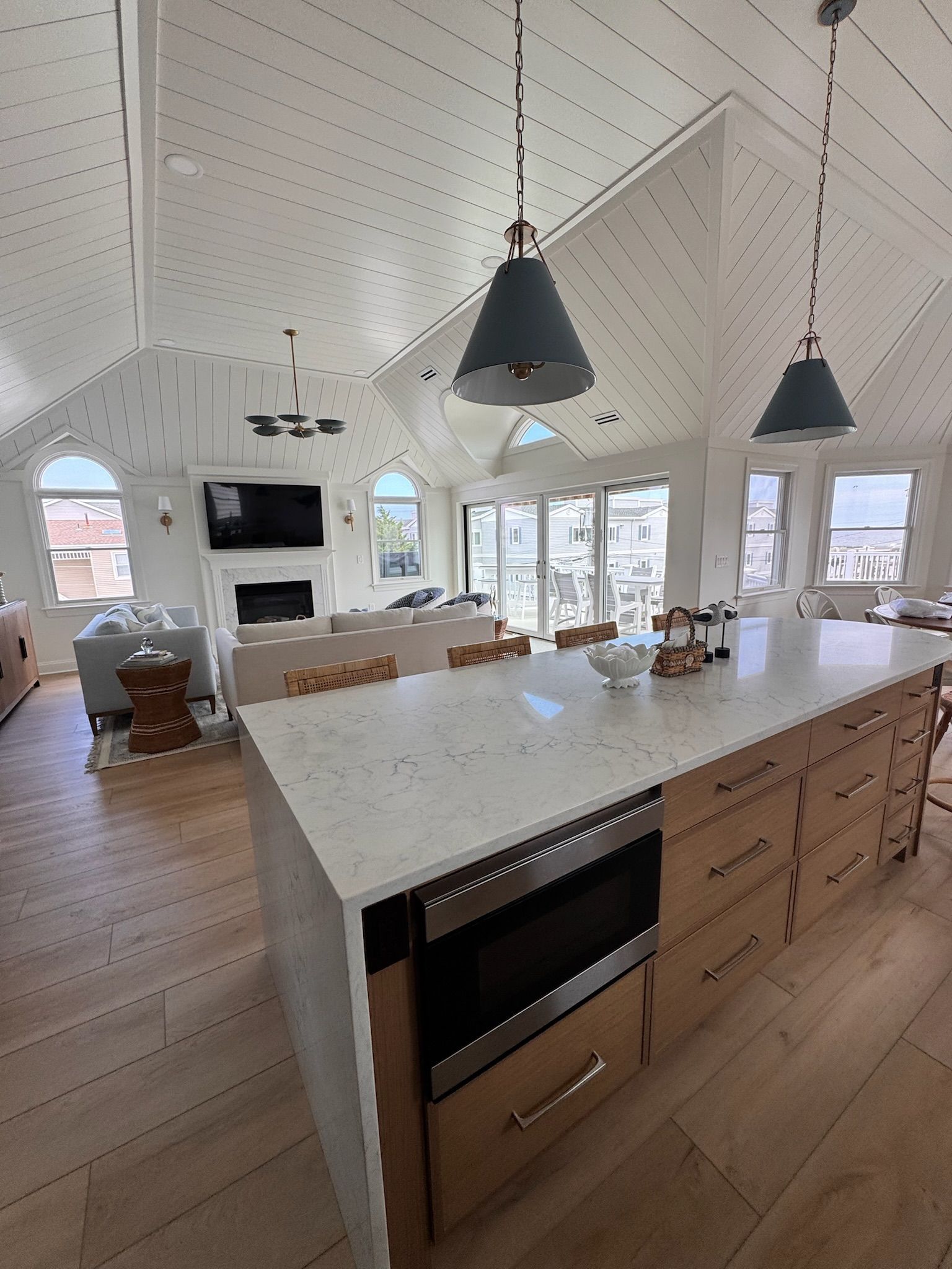 Spacious kitchen with large island, pendant lights, light wood cabinets, and white walls.
