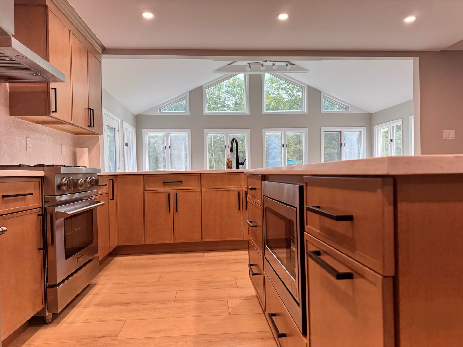 Kitchen with light brown cabinets, stainless steel appliances, and view of windows.
