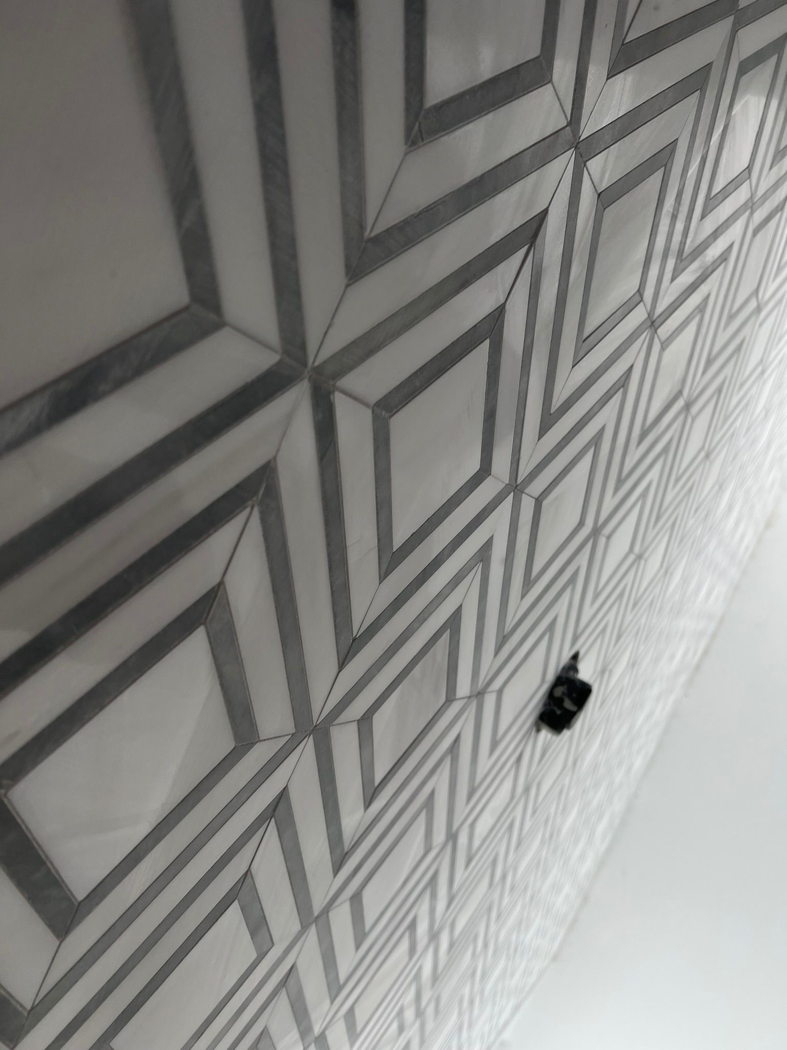 Geometric patterned white and gray wall tiles.