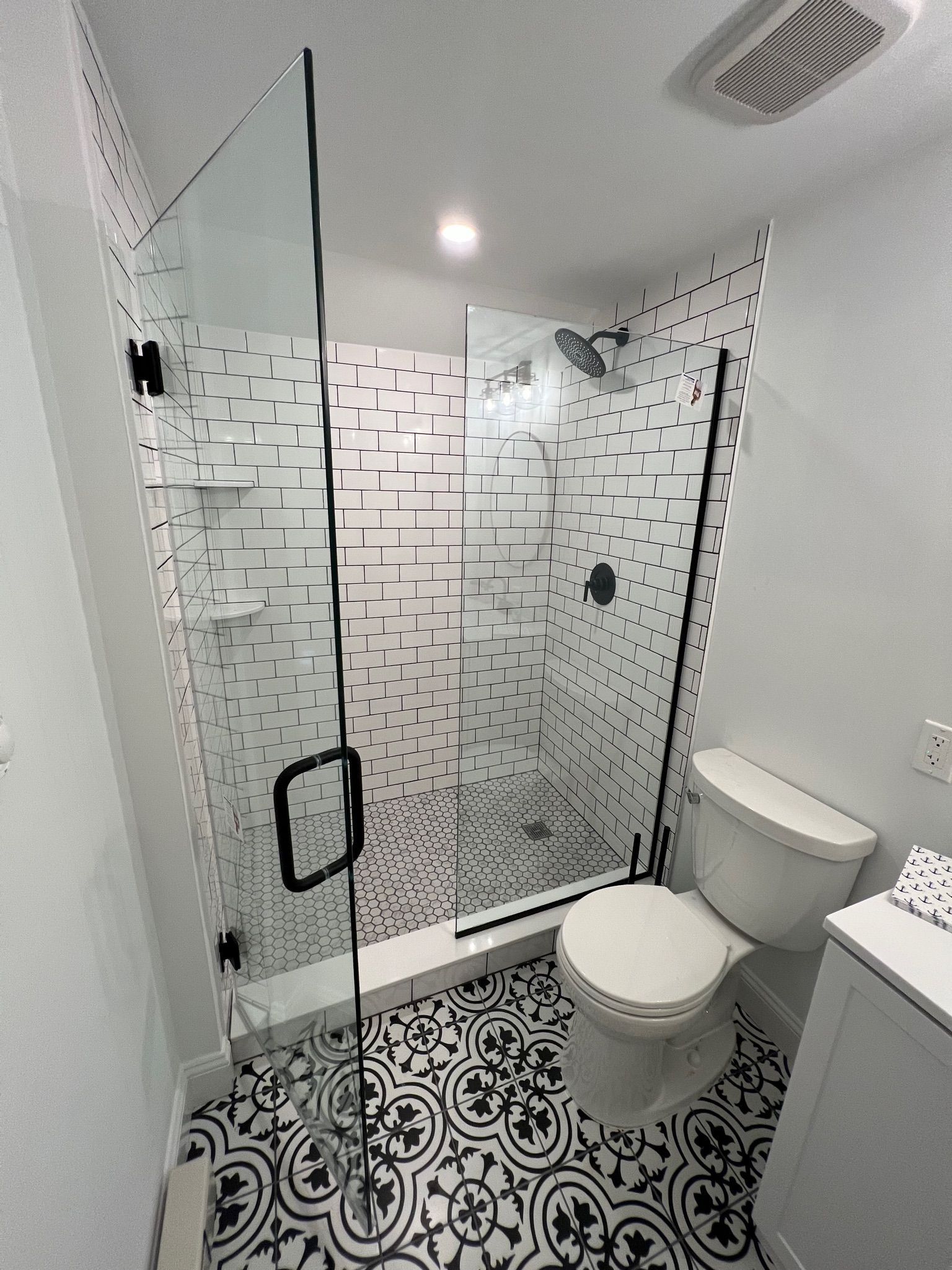 Modern bathroom with black and white patterned tile floor and shower with patterned wall.