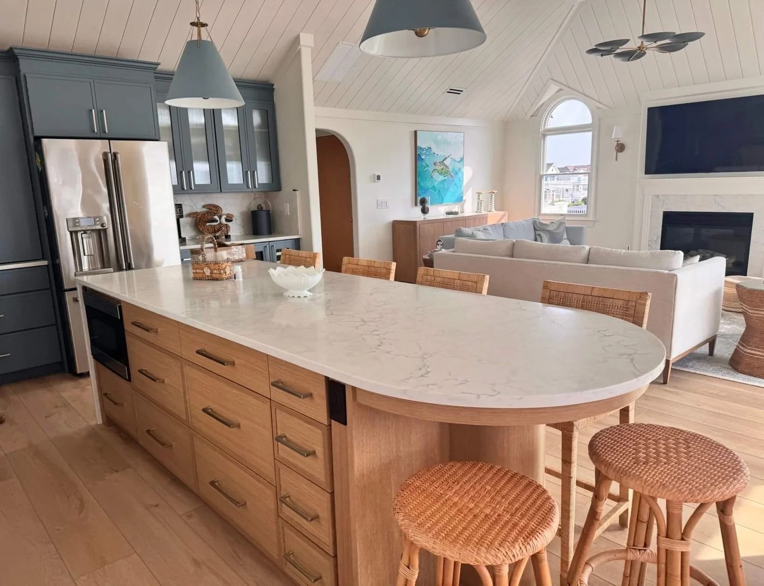 Kitchen with large wooden island, light-colored countertops, blue cabinets, and wicker stools.