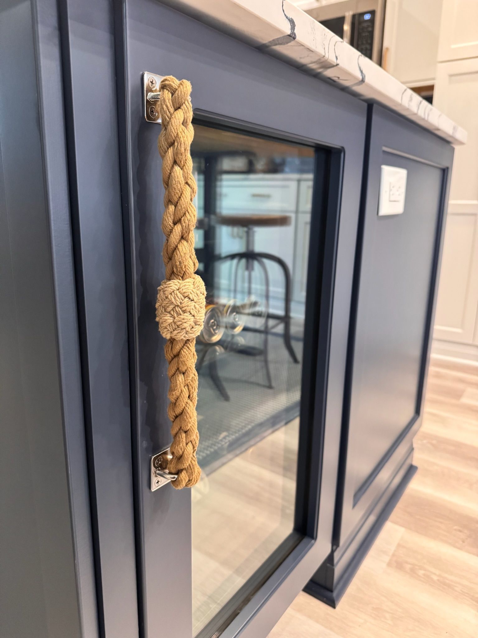Navy blue kitchen island cabinet with a nautical-style, braided rope handle and a decorative knot center.