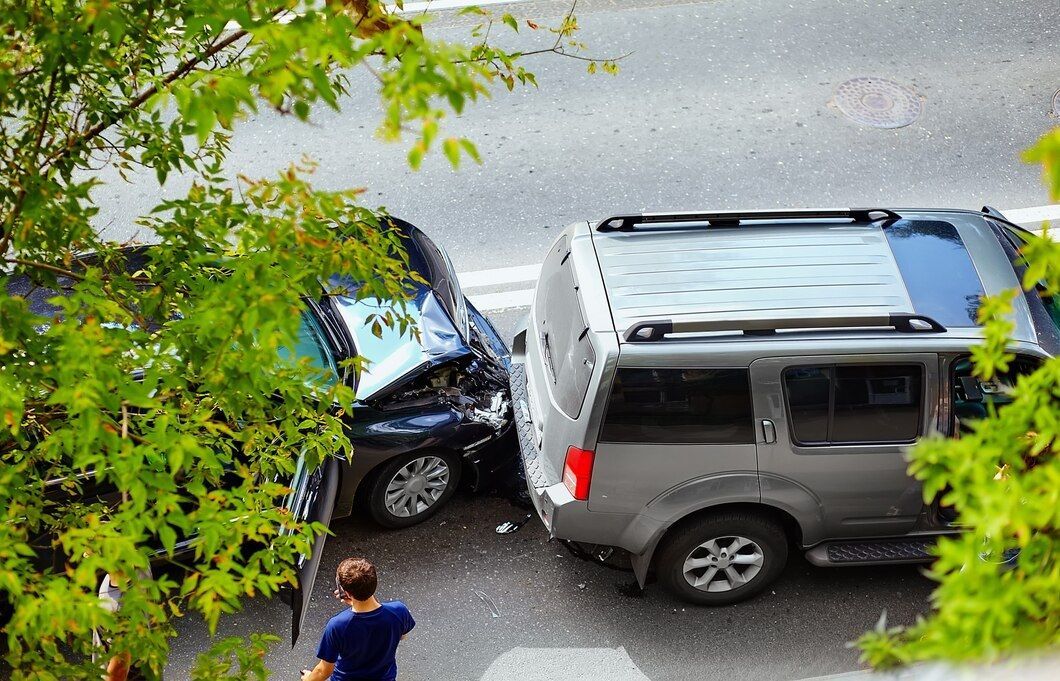 A man is standing next to a car that has crashed into another car.