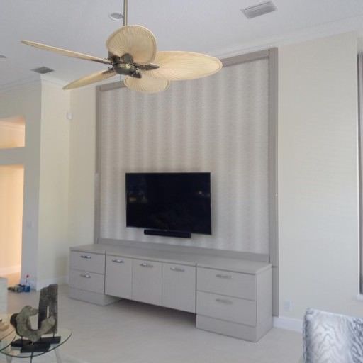 a living room with a flat-screen tv and a ceiling fan