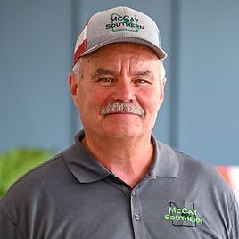 Bob McCay with a mustache is wearing a hat and a polo shirt.