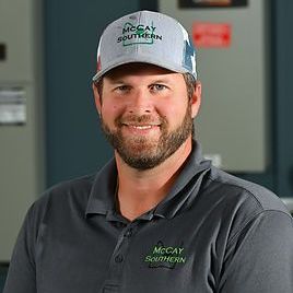 Justin Liner with a beard is wearing a hat and smiling for the camera.