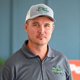 Rob McCay wearing a hat and a polo shirt is standing in a room.