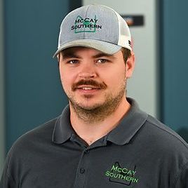 Will McCay with a mustache is wearing a hat and a polo shirt.