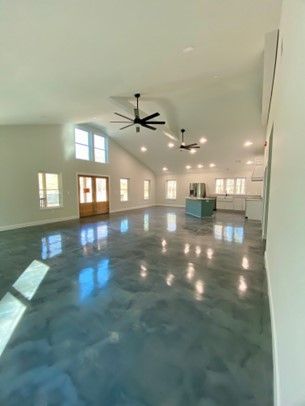 A large empty room with a ceiling fan and a concrete floor