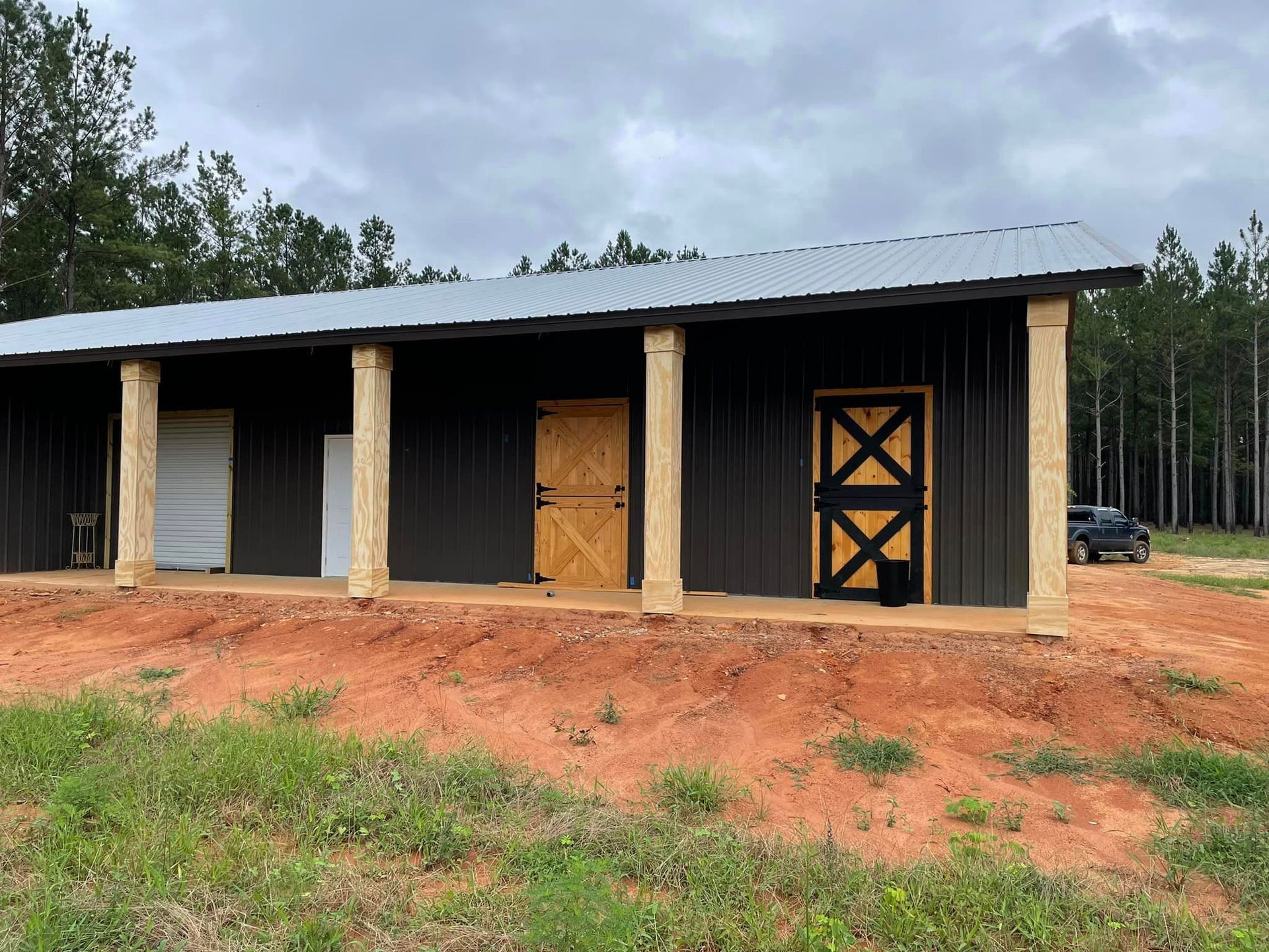 a black barn with a wooden door and pillars