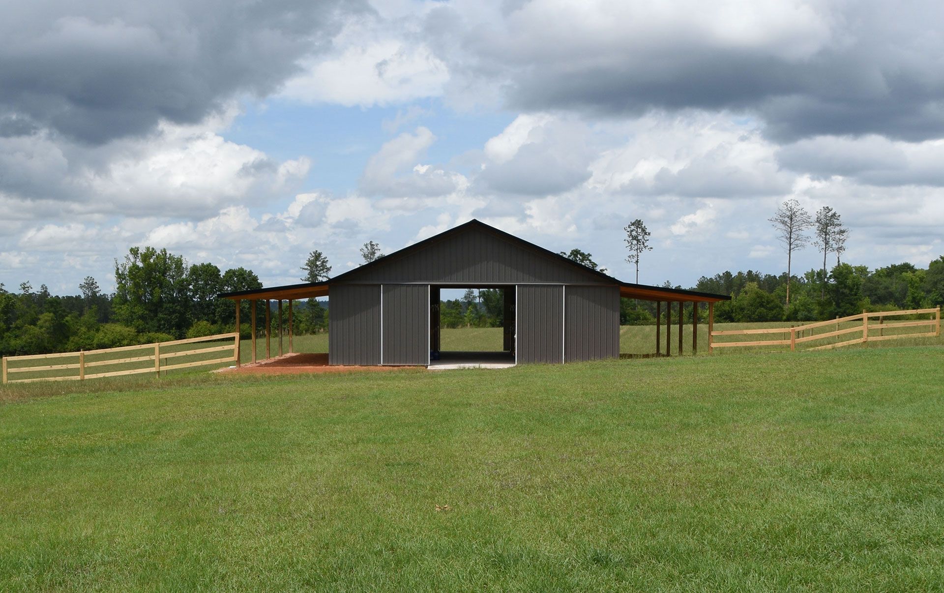 A pole barn is sitting in the middle of a grassy field