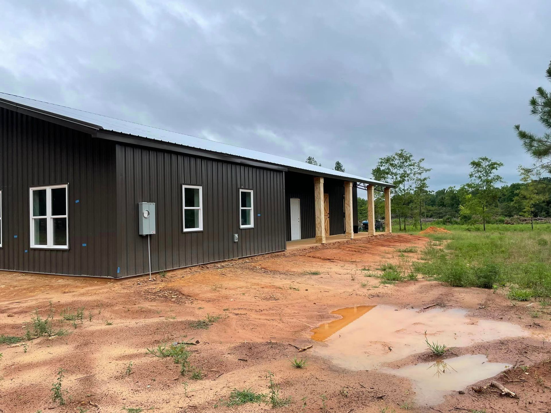 a brown barn with white windows and an electrical box on the side