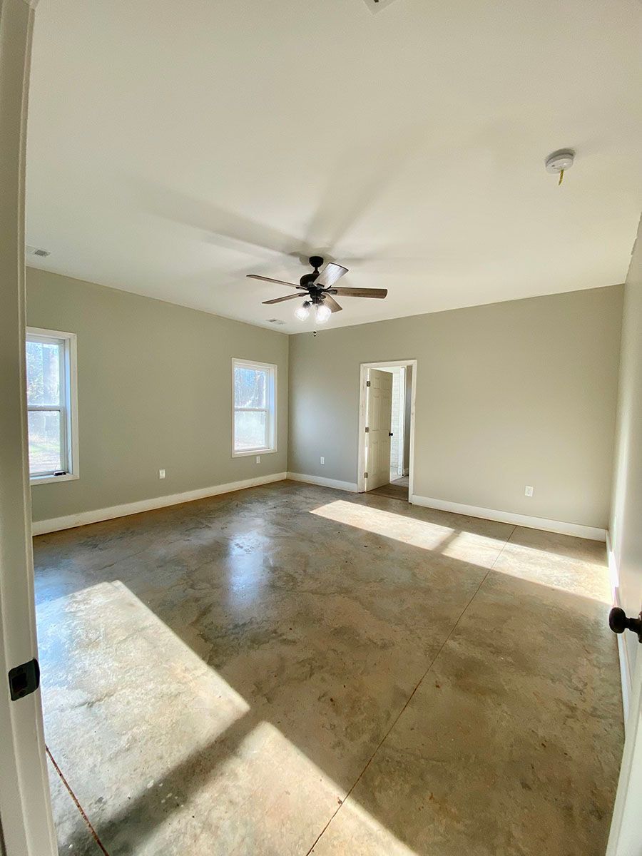 A large empty room with a ceiling fan and windows