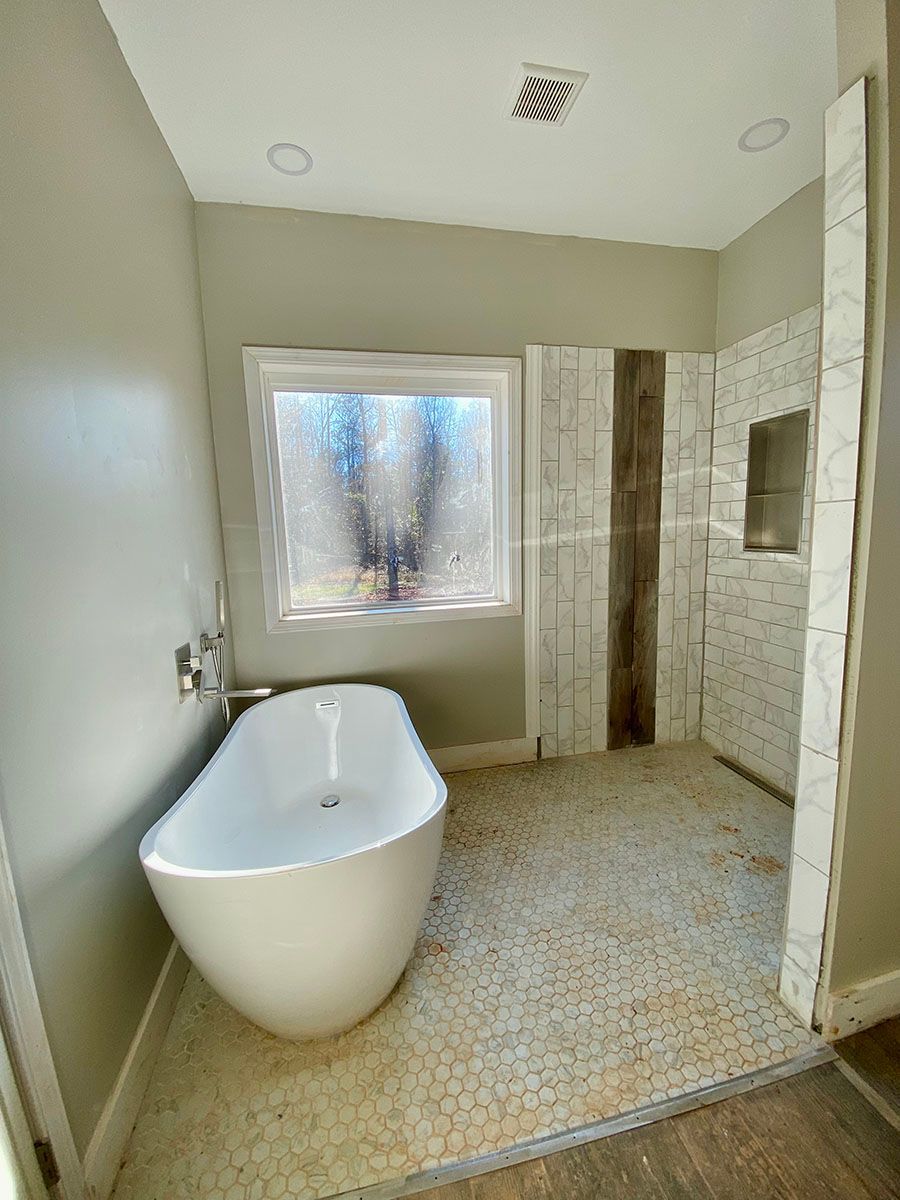 A bathroom with a tub, shower, and window