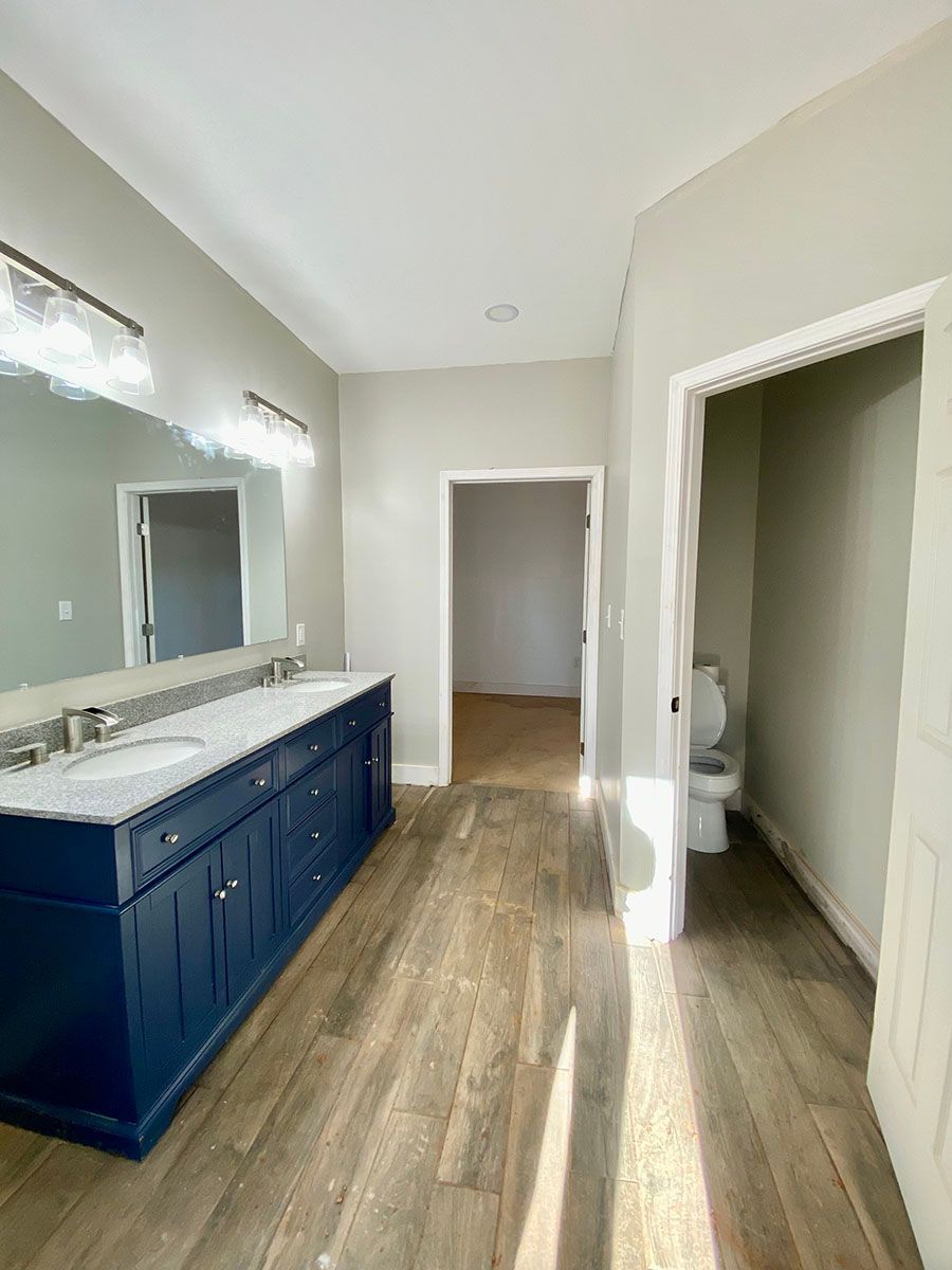 A bathroom with two sinks, a toilet, and a mirror 