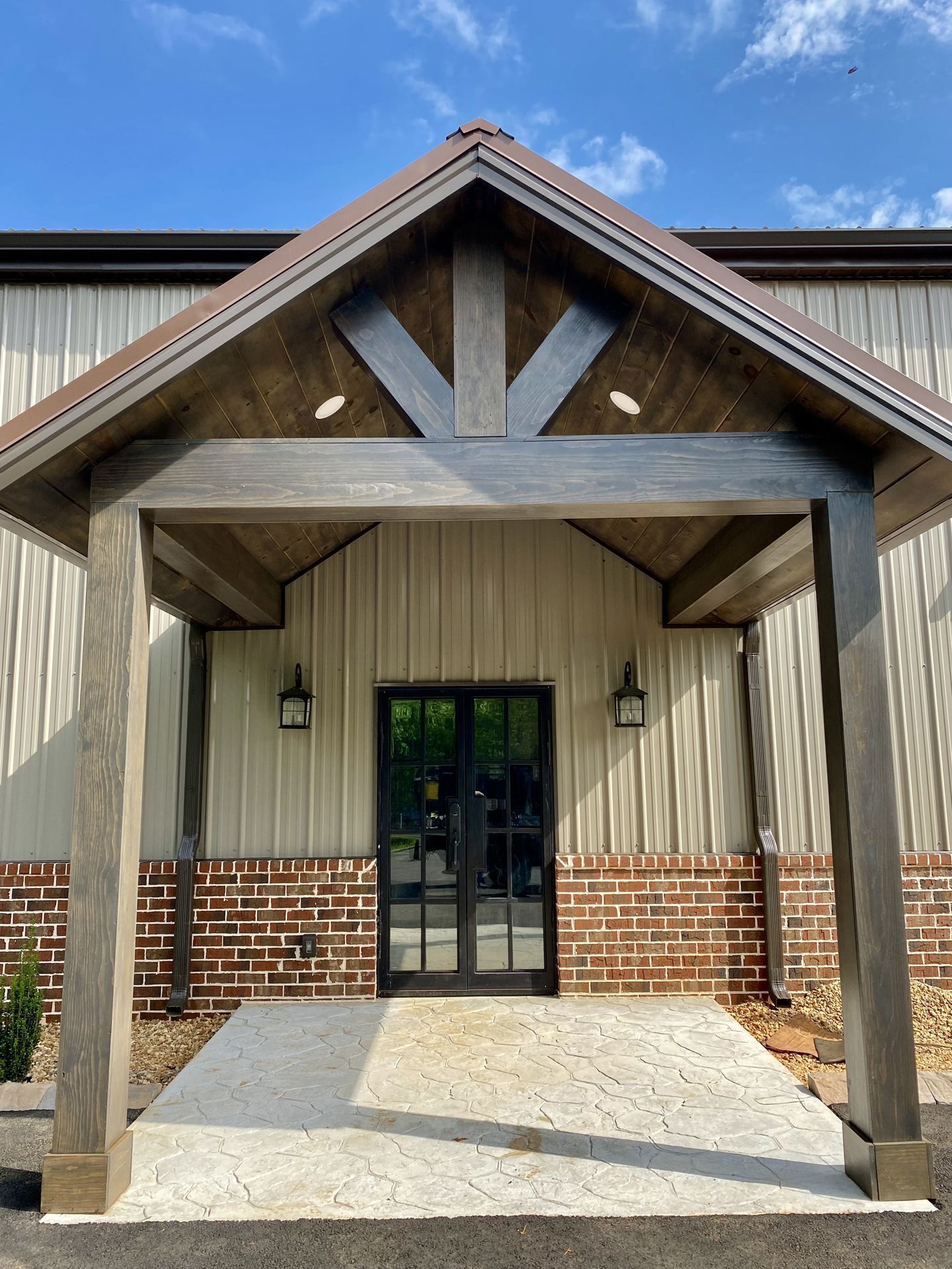 The front of a building with a wooden porch and a brick wall