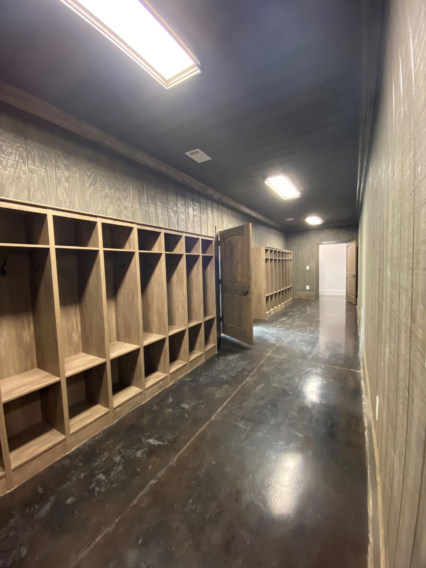 A long hallway with wooden shelves and a door