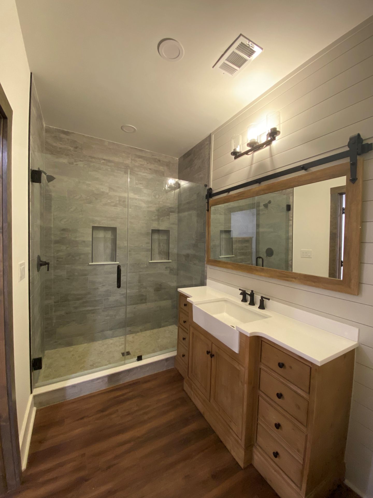 A bathroom with a sink  mirror, and walk in shower