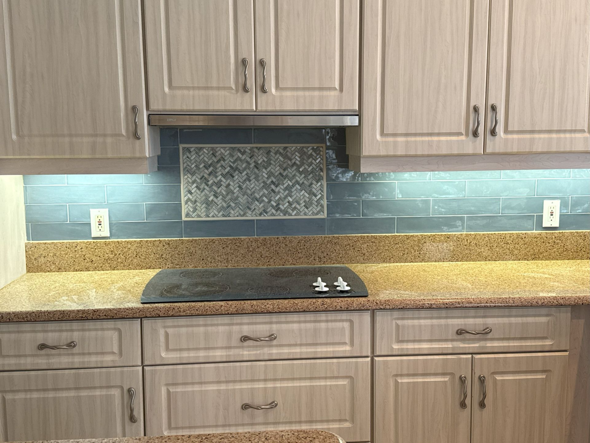 A kitchen with white cabinets , granite counter tops , and a stove top oven.