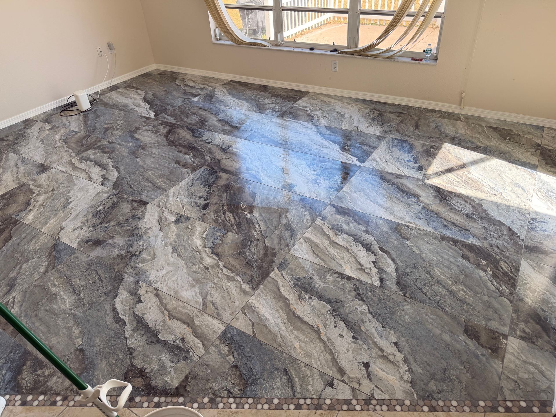 Room with newly installed gray and brown patterned flooring, window in background.