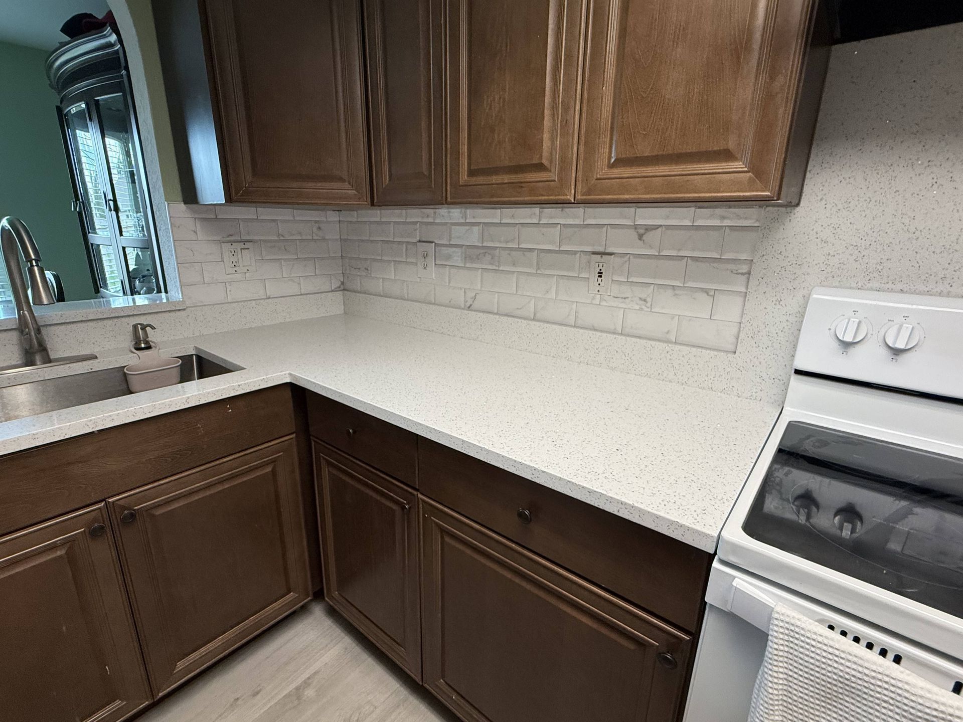 Kitchen with dark brown cabinets, white countertops, white tile backsplash, and white appliances.