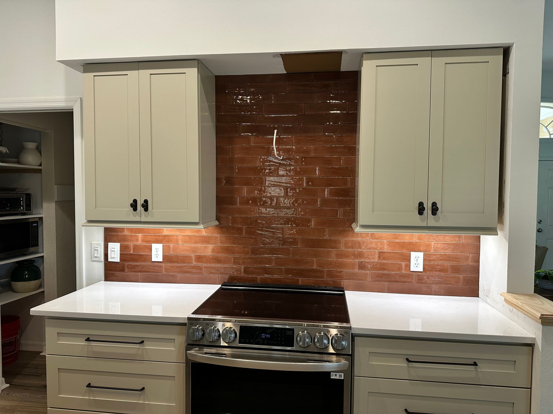 Kitchen with beige cabinets, brick backsplash, stovetop, and white countertop.