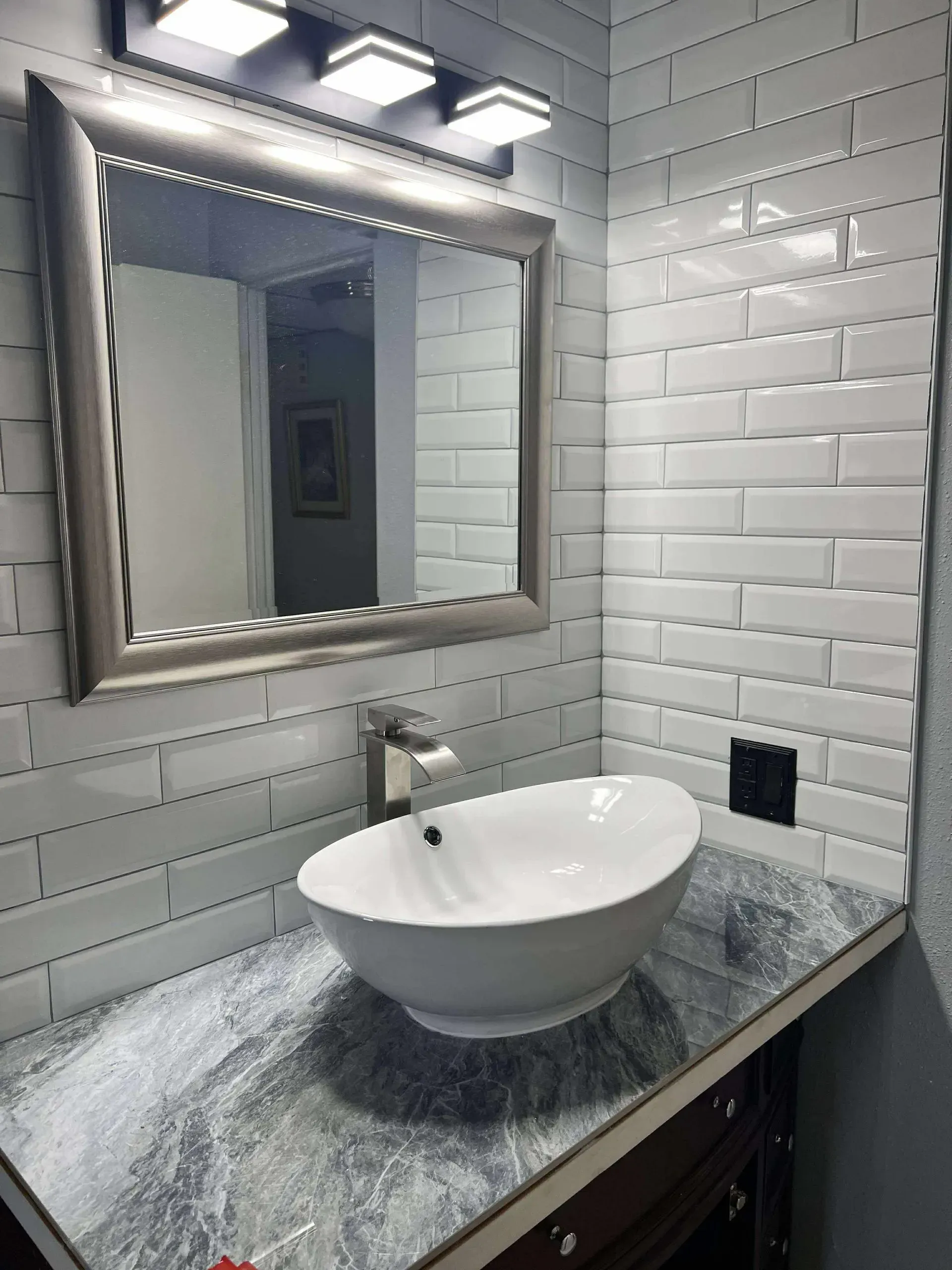 Bathroom with white subway tile, oval sink, and marble countertop.