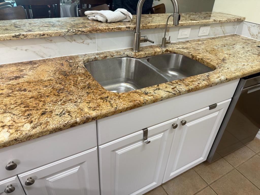 White cabinets with granite countertop and stainless steel double sink.