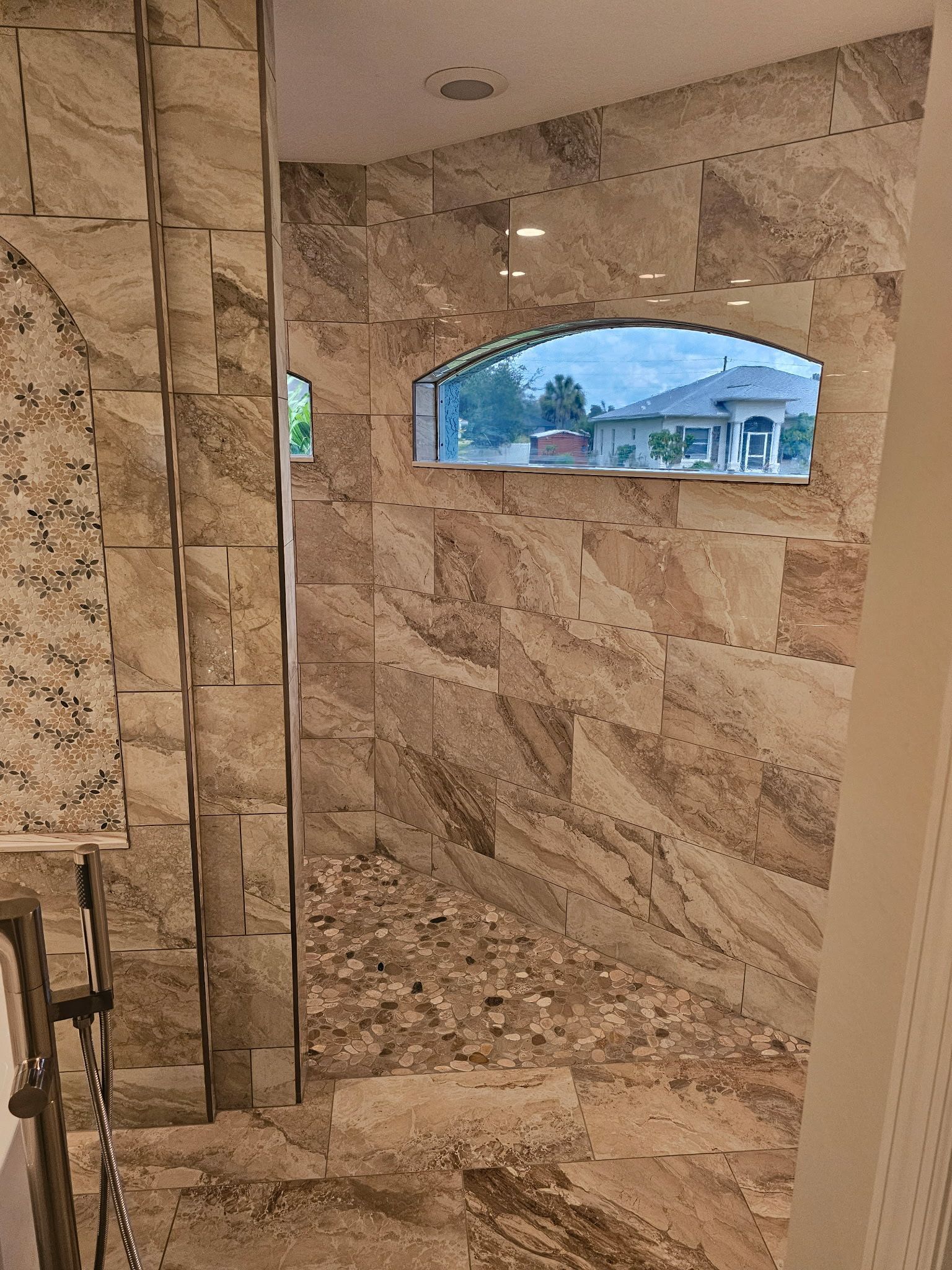 A bathroom with a walk in shower and a window in the wall.