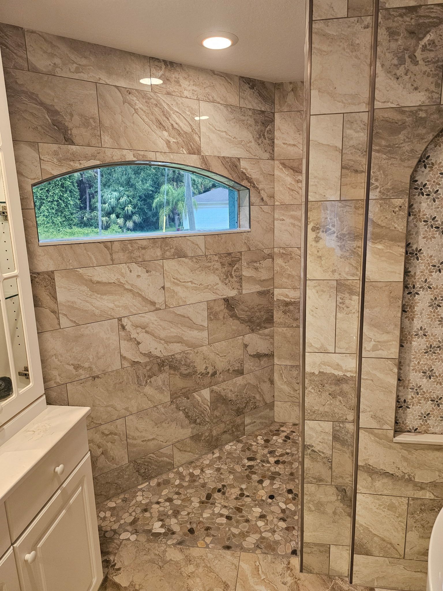 A bathroom with a walk in shower and a window.