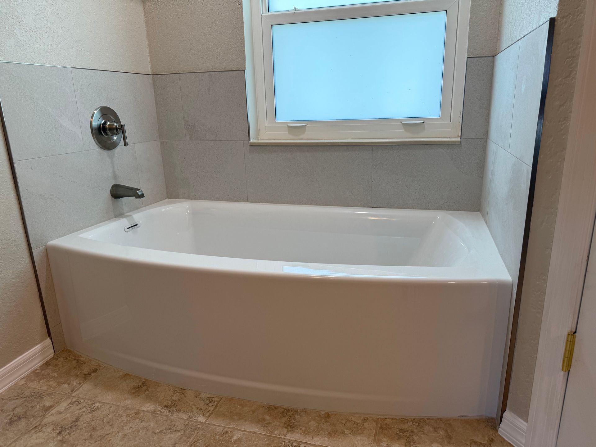 A bathtub in a bathroom next to a window