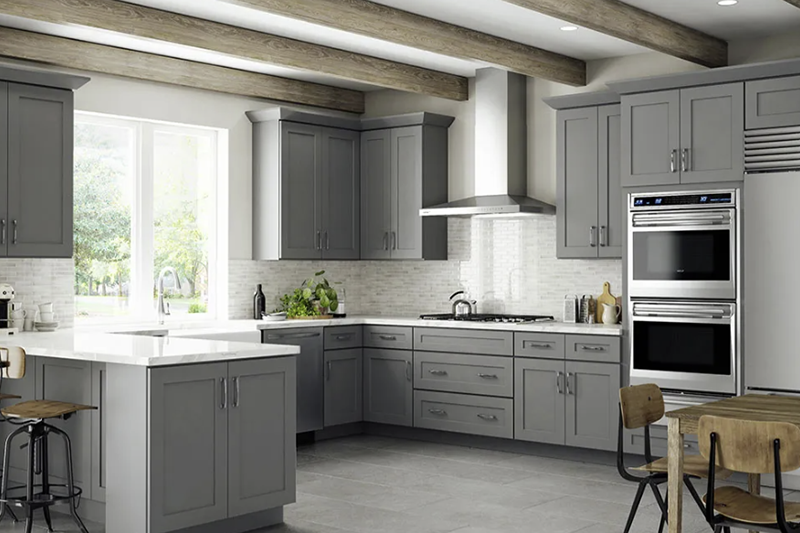 Bright gray kitchen with white countertops, wood beams, and a large window over the sink.