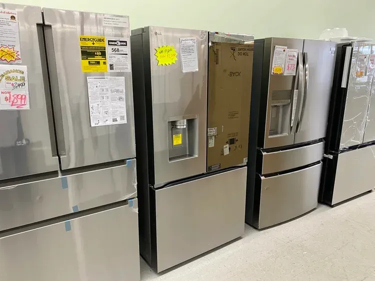 Stainless steel refrigerators on display in a store, some with water dispensers and energy labels.