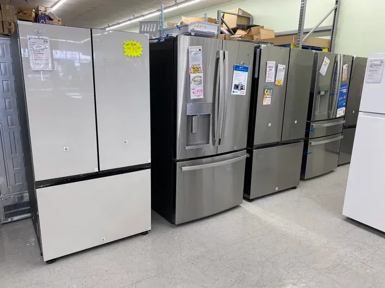 Lineup of refrigerators in a store, various stainless steel and white models.