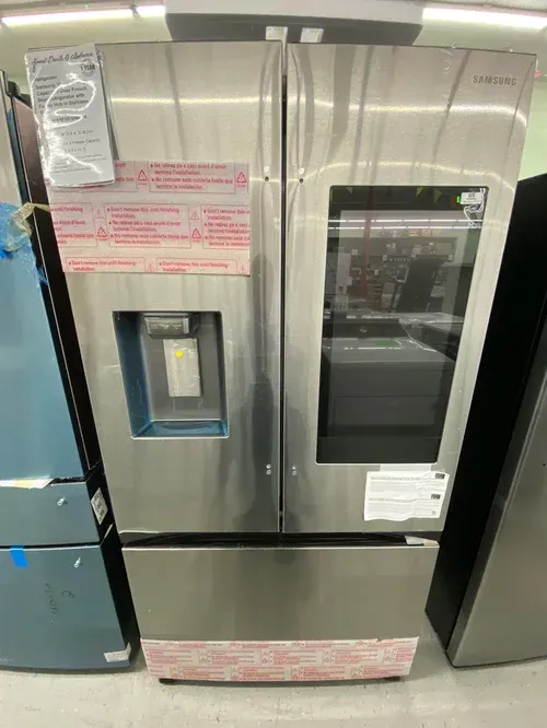Stainless steel Samsung refrigerator with ice/water dispenser, window panel, and protective tape.