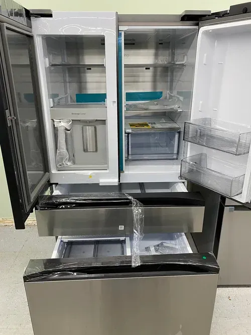 Stainless steel, four-door refrigerator with open doors. The interior shows shelves, drawers, and an ice/water dispenser.