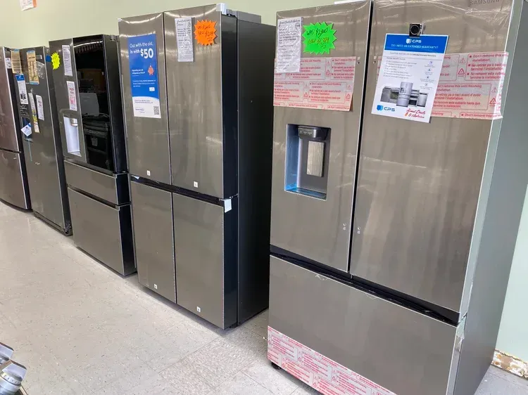 Row of stainless steel refrigerators on display in a store.