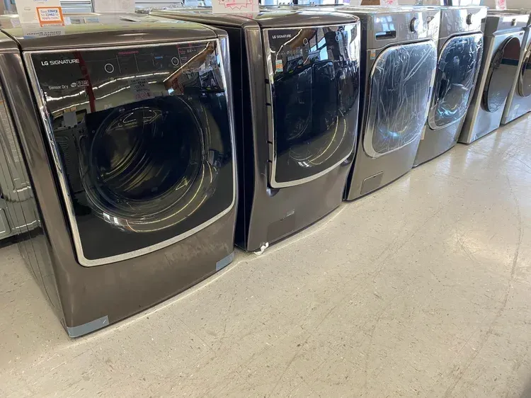 Row of brown washing machines and dryers on display in a store.