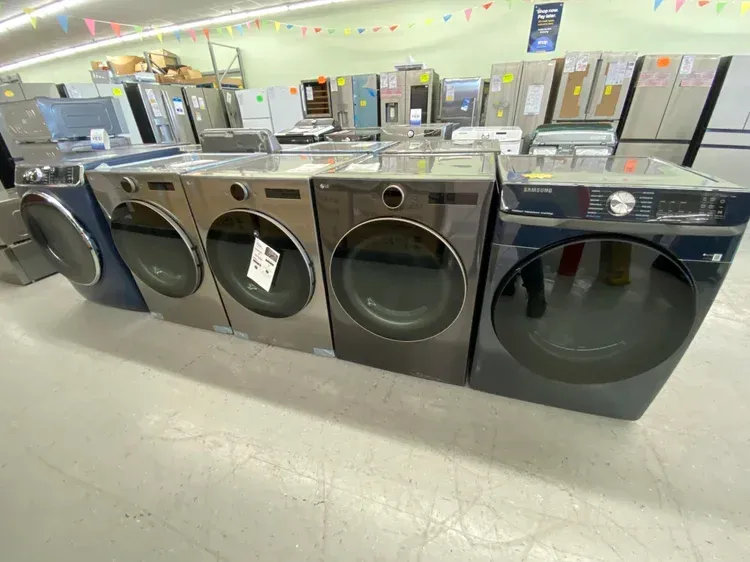 Row of dark-colored washing machines and dryers for sale in an appliance store.